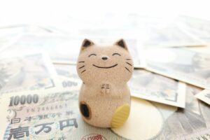 沢山の一万円札の上の猫の置物